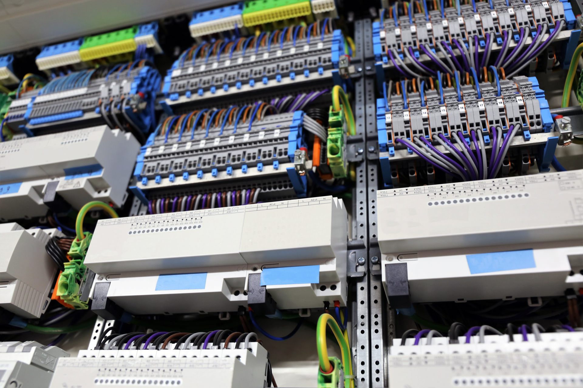 Detailaufnahme eines professionell verdrahteten Schaltschrankes mit Reihenklemmen, Steuerungen und farblich sortierten Kabeln.